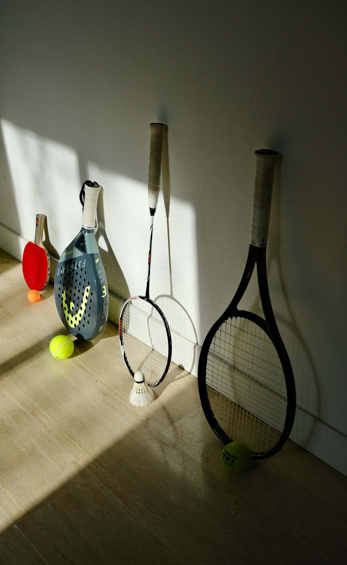 Three tennis rackets and two tennis balls on the floor